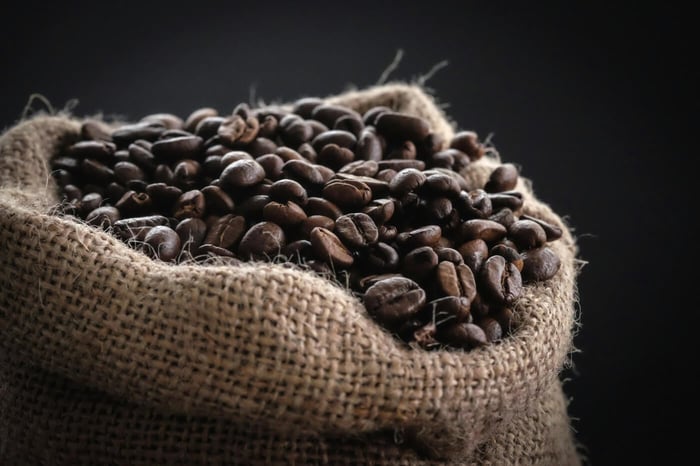Dark coffee beans spilling from a burlap sack
