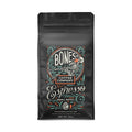 The front of a 12 ounce coffee bag for espresso. The Bones Coffee Company logo is on it and has a skeleton lounging in greenery and sipping on coffee.