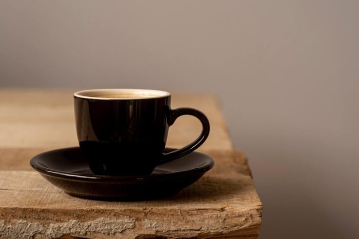 Black coffee cup on wooden surface. 