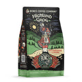The front of a 12 ounce bag of Bones Coffee Company Highland Grog coffee. Its flavor is caramel and butterscotch, and it has a skeleton wearing a kilt playing bagpipes on a hill on the art.