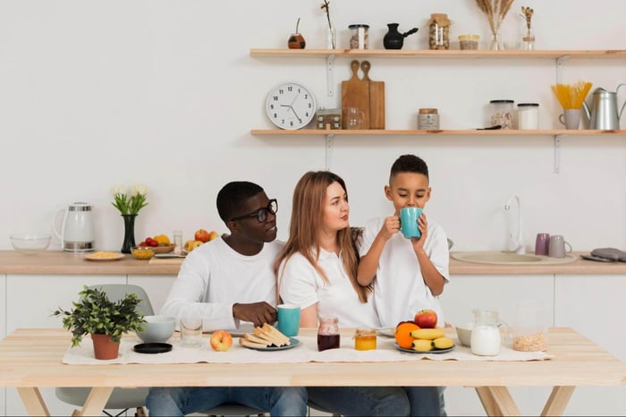 happy family with kid drinking from mom’s coffee mug in kitchen