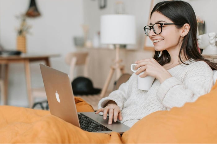 woman with white top drinking coffee while working