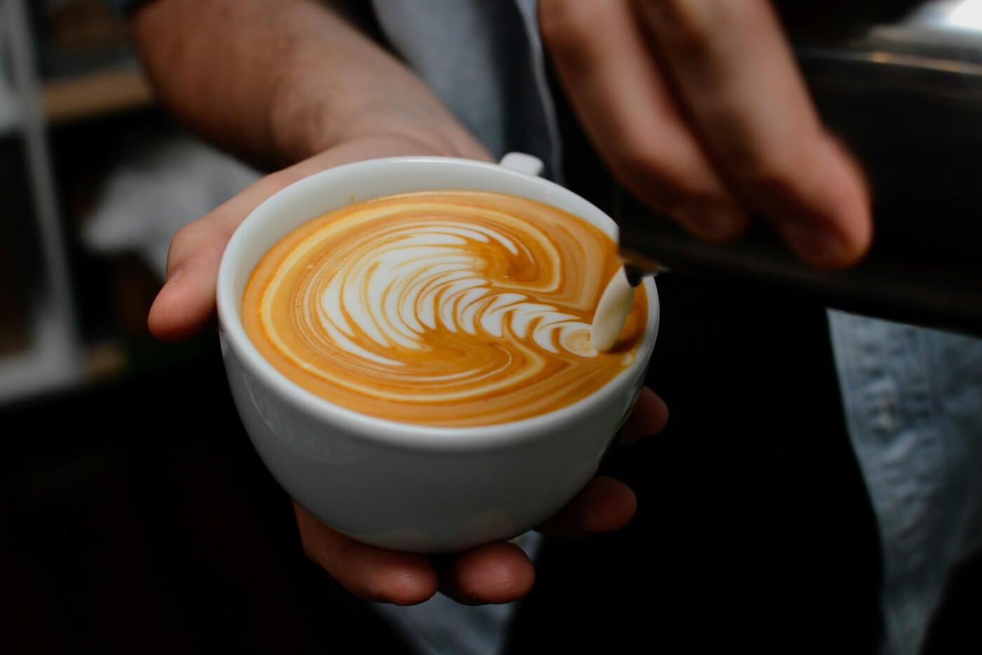 milk being poured into a cup of coffee