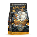 The front of a 12 ounce bag of Bones Coffee Company Salted Caramel coffee. Its flavor is salted caramel, and it has a skeleton dressed up as pirate on the bow of the ship with a treasure chest of salted caramel behind it on the art.