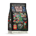 The front of a 12 ounce bag of Bones Coffee Company Sugar Rush coffee. Its flavor is sugar cookie. It has skeletons dressed as elves in a toy workshop on the art.