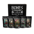 Five four ounce packs of coffee. From left to right their names are Costa Rica, Sumatra, Ethiopia, Colombia, Guatemala. There is a box behind it featured the Bones Coffee Company logo.