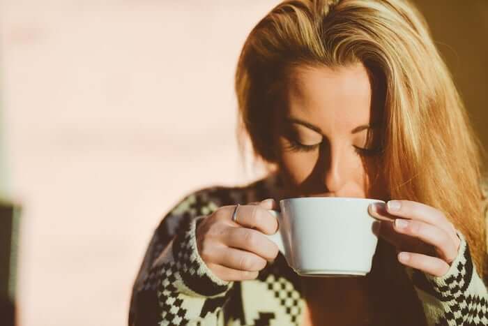 Young woman enjoying a warm drink in morning sunlight.